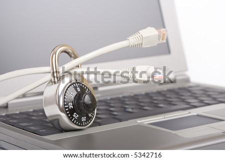 Closed padlock on network cables on a laptop - over a white background