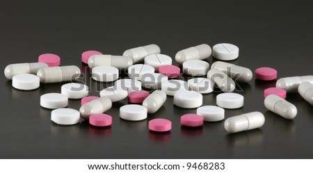 Red and white tablets and pills isolated on a black background