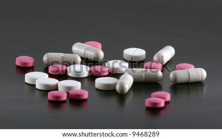 Red and white tablets and pills isolated on a black background