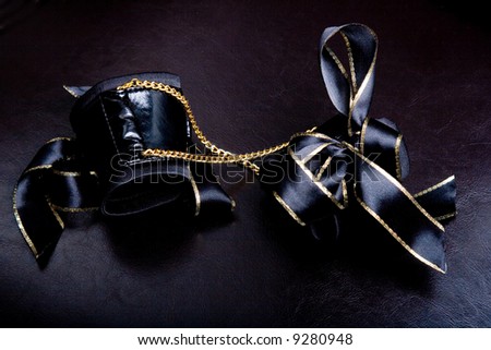 Leather handcuffs with golden chains on dar background