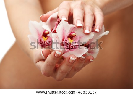 Closeup of young woman hands with magenta orchid over her slim body