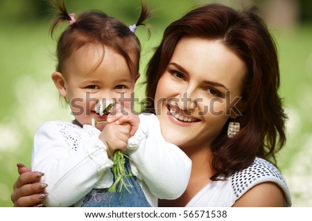 Young mother with child outside on a summer day. Focus is on the woman.