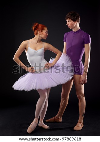 Couple of ballet dancers posing over dark background
