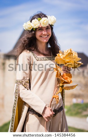 KHOTYN, UKRAINE - MAY 10: Girl dressed in historical clother with artifical flower smiles to reporter at Medieval Khotin Festival. Khotyn, Ukraine, 10 May 2013