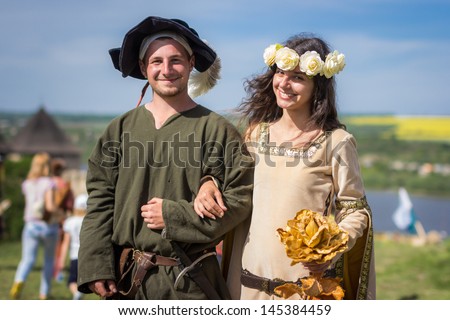 KHOTYN, UKRAINE - MAY 10: Man and girl dressed in historical clother smiles to reporter at Medieval Khotin Festival. Khotyn, Ukraine, 10 May 2013