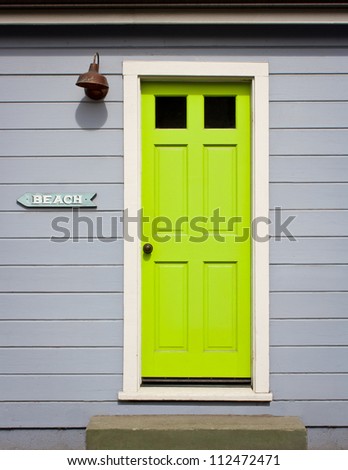 A bright, lime green door with white wood trim in a light gray wood sided home exterior, including a \
