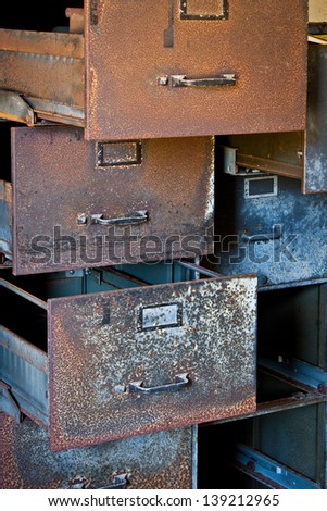 A rusty filing cabinet with empty drawers, pulled open.
