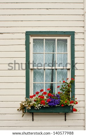 A window of an old house with a flower planter box.