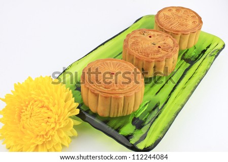 Moon cakes served on green plate with yellow chrysanthemum.