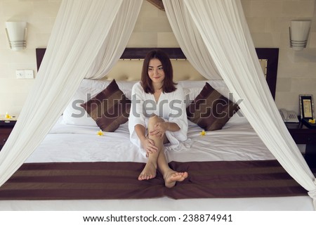 The girl irons the legs siting on a bed.