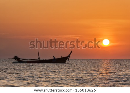 silhouette of fishermen with fishing boat at sunset.
