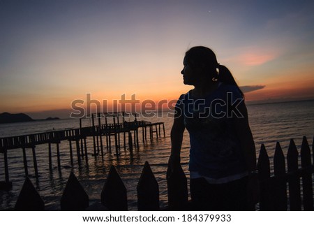 woman standing on wooden bridge and looking away. sunset.