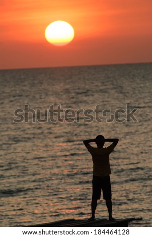 Man with his hands up watching the sun set