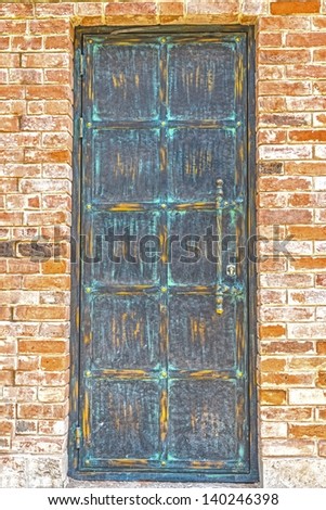 bronze door in the brick wall with the right-hand door handle