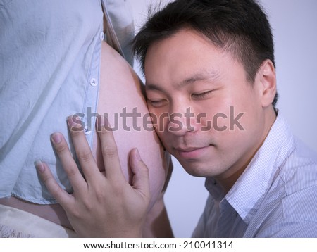 Man touch  wife\'s abdomen and close eye./man love his baby