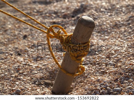 Wooden peg tent tied yellow solid thread, and scored in the sand
