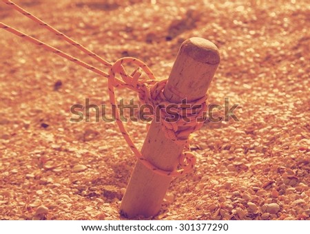 Wooden peg tent tied yellow solid thread, and scored in the sand retro
