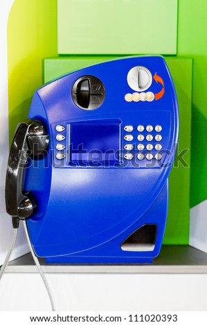 Blue public landline payphone on green background