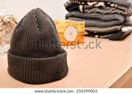 woolen cap on a wooden table with sweaters background
