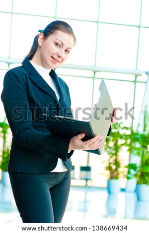 Young happy business woman with an open folder in hand