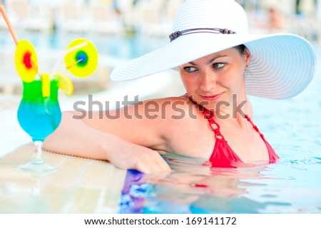 Luxurious woman in a hat and cocktail