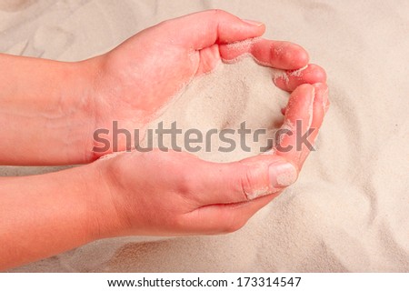 fine sand flowing out of women\'s hands