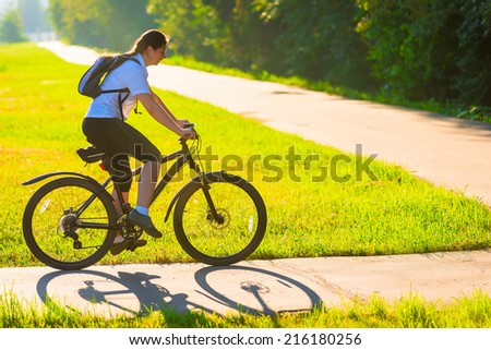 girl on bike rides on the bike path in the park