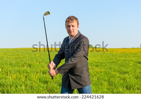 man in a business suit holding a golf club