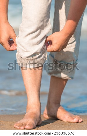 men legs in linen trousers on background of the sea