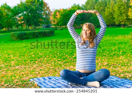 Pregnant woman doing fitness outdoor in a park