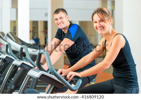 Portrait of a happy couple on a stationary bike in the gym