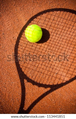 Tennis ball  with racket shadow over