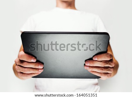 Man in white t-shirt using tablet pc, white wall on background