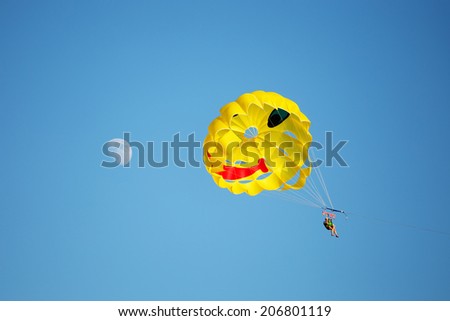 A parachute being towed at sea with a clear blue sky in the background. Moon on the left.