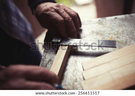 Old carpenter taking measurement of a wooden plank, retro tinted
