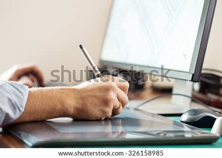Graphic designer using digital tablet and computer in office or home