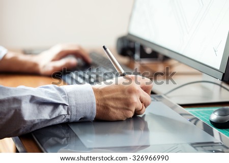 Graphic designer using digital tablet and computer in office or home
