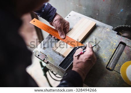 Old carpenter taking measurement of a wooden plank