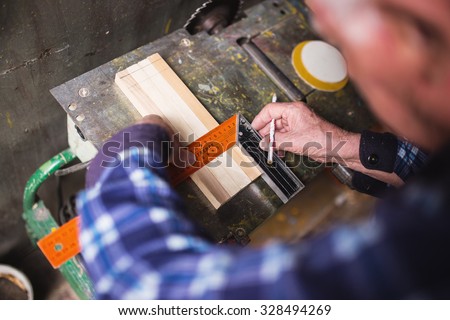 Old carpenter taking measurement of a wooden plank