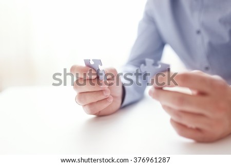 Businessman hands connecting jigsaw puzzle. Business solutions, success and strategy, learning concept. Close up photo with small dof