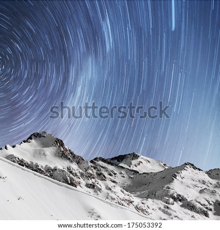 Star trails above snow capped mountains