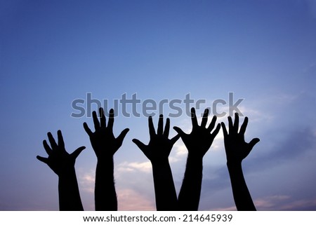 volunteer group raising hands against blue sky background