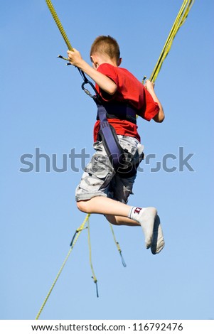 Little boy jumping on the trampoline (bungee jumping).