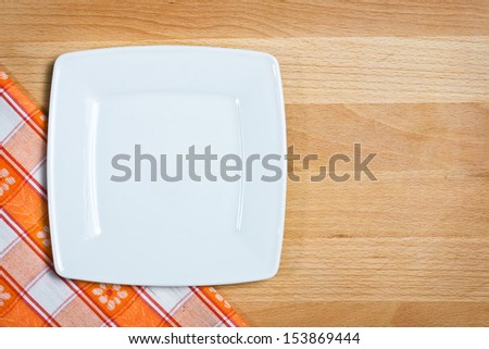 Empty plate on tablecloth over wooden background