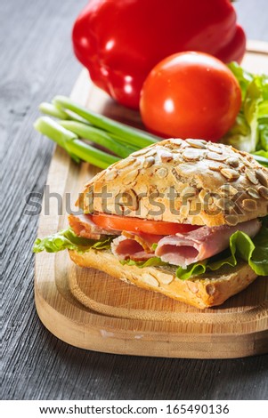 Fresh ham sandwich on wooden board - close up