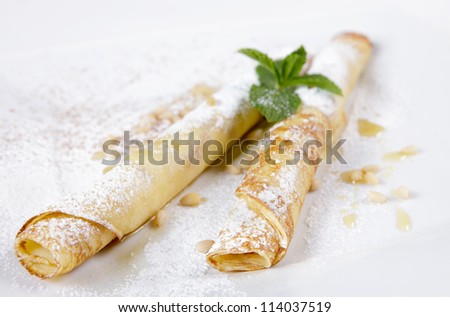 pancakes with maple syrup, pine nuts and sprinkle with powdered sugar. Some ingredients in the background