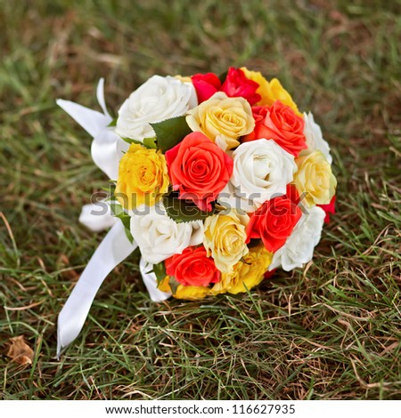 wedding flowers - Wedding bouquet of yellow and white roses and blue fresia lying on the grass in the park outdoors