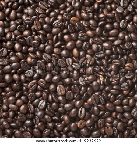 A lot of roasted coffee beans which have been scattered all over the surface used as a background - square