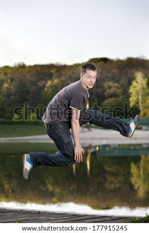 The young man jumped up on a background of lake