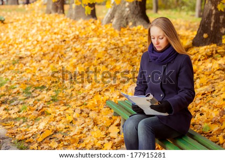 woman in autumn park reading a magazine